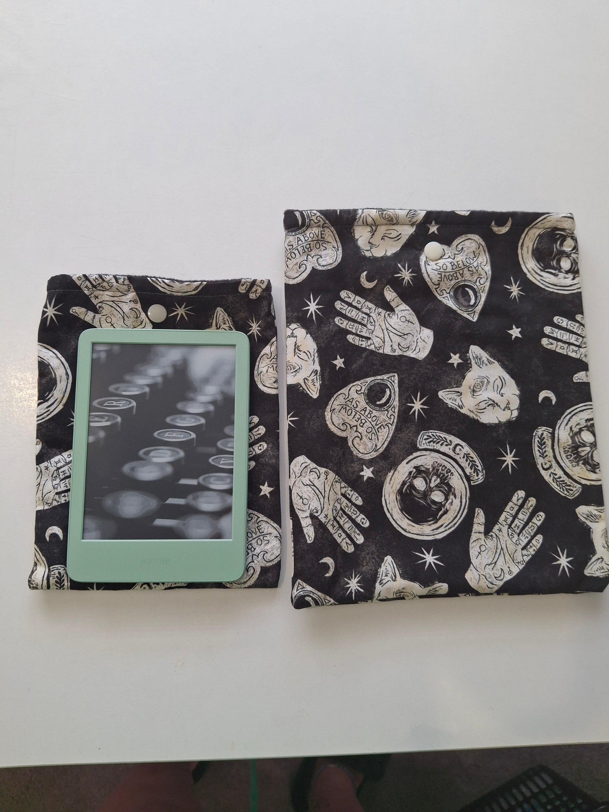 Black fabric with white celestial and hand designs, folded on a white surface.